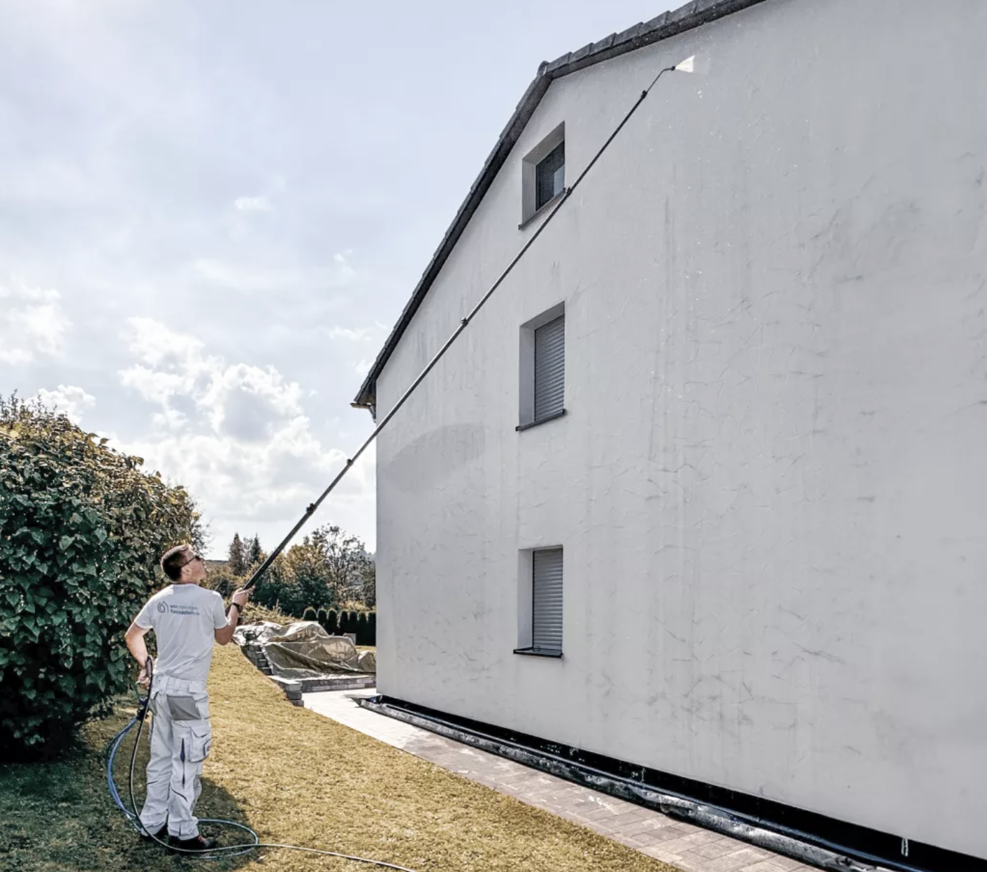 Techniker reinigt eine Hausfassade mit einer 10 Meter langen Teleskoplanze
